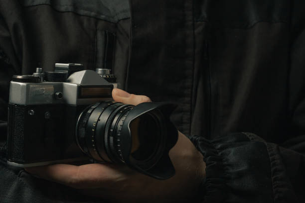 istock man holding Retro film photo camera isolated on black background soviet 1444931023