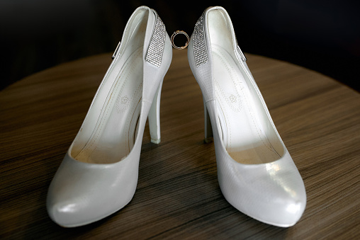 Wedding rings and shoes on background