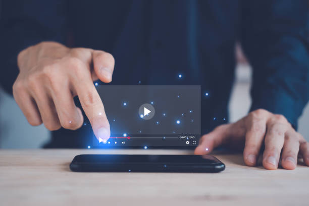 istock Video streaming online on smartphone with hologram. Man using smartphone on vacation. Social media and digital online concept. 1444937334