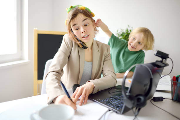 young woman working online using laptop at home. home office and parenthood at same time. exhausted parent with hyperactive child. mischievous kid of mother freelancer. - inconvenience meeting business distracted imagens e fotografias de stock