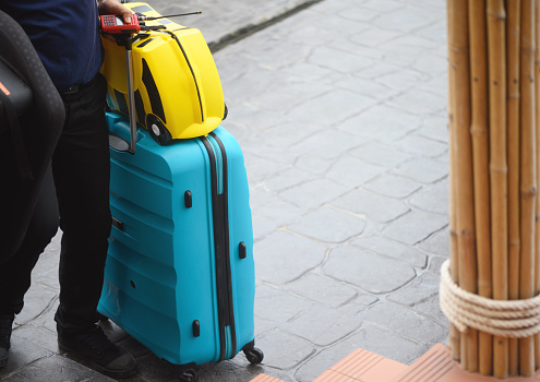 Unrecognizable porter bringing luggage into the hotel, copy space