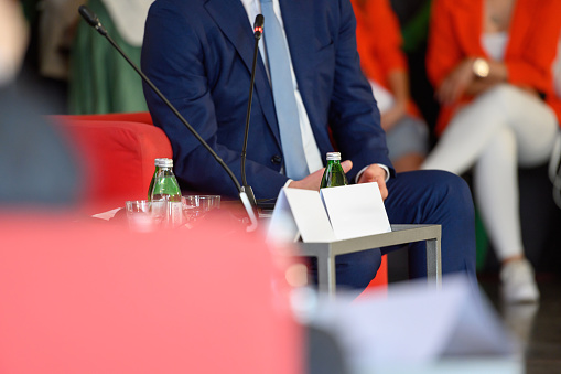 Front view of diverse group of business professionals listening to speaker at a business seminar in modern office building