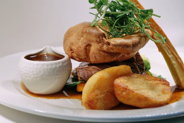 Traditional British Sunday roast, roasted beef with Yorkshire pudding, roasted potatoes and gravy.