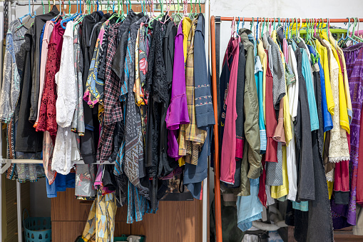 Lots of old, colorful clothes hung chaotically on the iron railings near the closets and baskets in the corners of an old concrete house in rural Thailand.