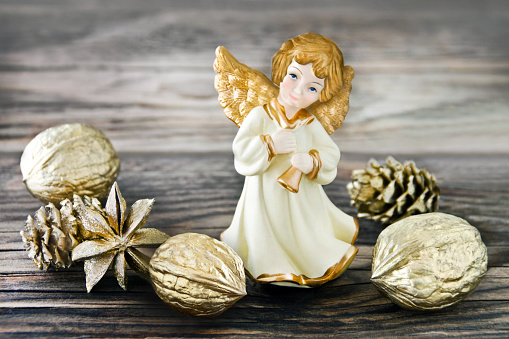 Chistmas Angel and golden decoration on wooden background