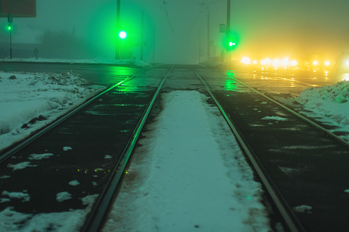 Tram rails. Foggy weather. Night fog. Poor visibility. Ray of light. Snow and ice. City street