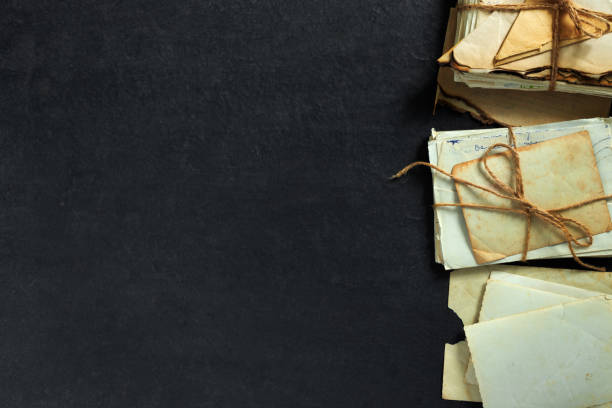 stack of old torn vintage letters on yellowed paper against black granite table. - writing manuscript ancient postcard imagens e fotografias de stock