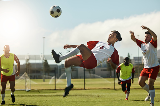 Soccer team, man and ball kick in air during football match, competition or training. Sports, fitness and soccer players on grass field together in practice game, exercise or workout outdoor on pitch