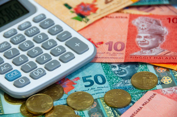 istock Close up of various Malaysia Ringgit currency and coins with calculator. 1444959606