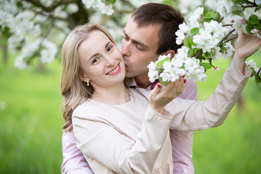 Young happy couple in love outdoors. loving man and woman on a walk in a spring blooming park