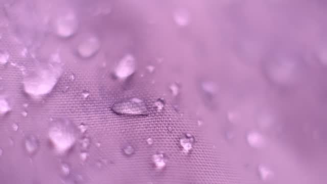 Slow Motion Shot of Water Splashing on waterproof fabric. water beading on fabric. Waterproof coating background with water drops. soft focus, blur