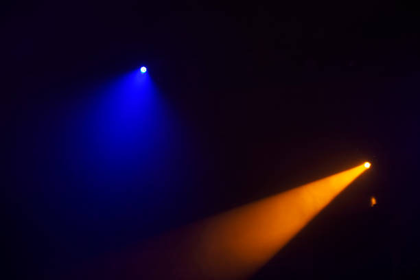 fasci di luce arancioni dai riflettori del palcoscenico su uno sfondo blu scuro. illuminazione del palcoscenico. - popular music concert lighting equipment illuminated stage foto e immagini stock