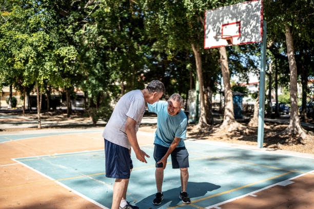 älterer mann mit beinschmerzen auf dem basketballplatz - mexico only men senior men mature men stock-fotos und bilder