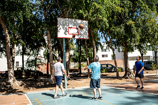 Mature man throwing sports ball at basketball hoop