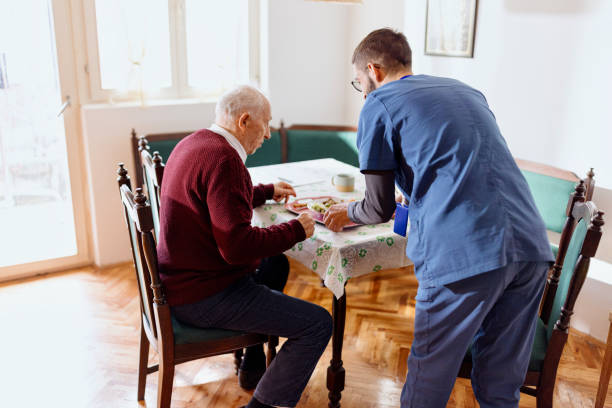 istock Care worker giving an old man lunch in his home. 1444971537