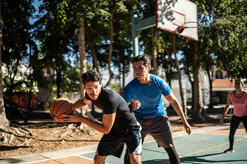 Young friends playing basketball at a basketball court