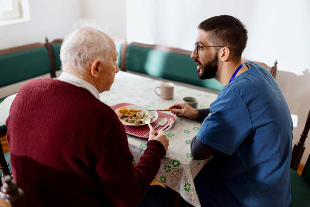 istock Caretaker helping man eat during lunch time 1444971673