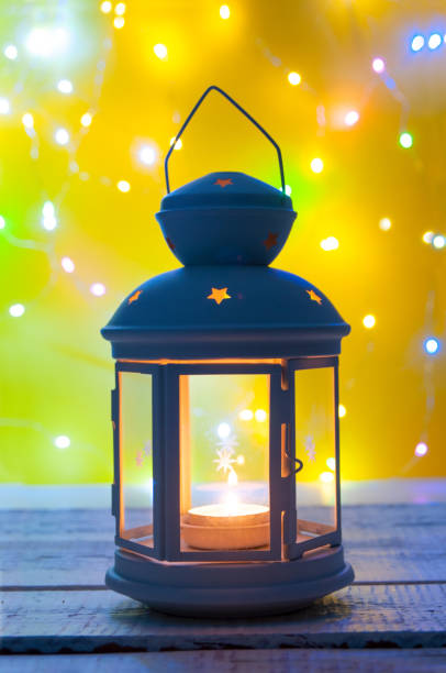 istock Christmas candlelight with glowing candle on yellow background with blurring garland 1444971801