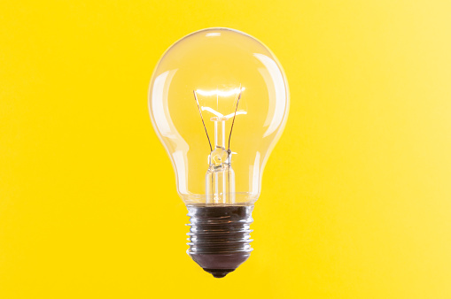 Old vintage light bulb close up on yellow background