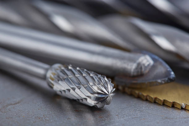 set of different drill bits,thread tap and mill cutters with caliper ruler on steel plate background. Locksmithing deal.