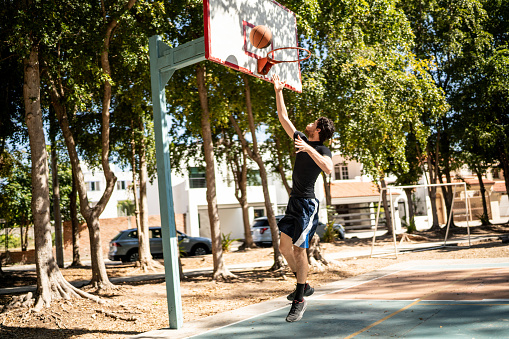 Young man doing a jump shot at the basketball court