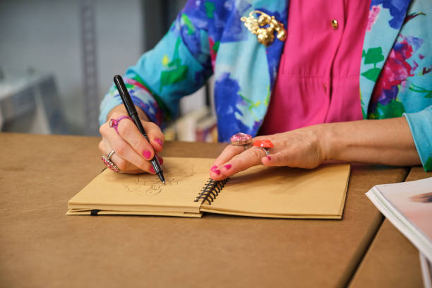 istock Unrecognizable dressmaker with colorfull clothes drawing new layout. 1444974303