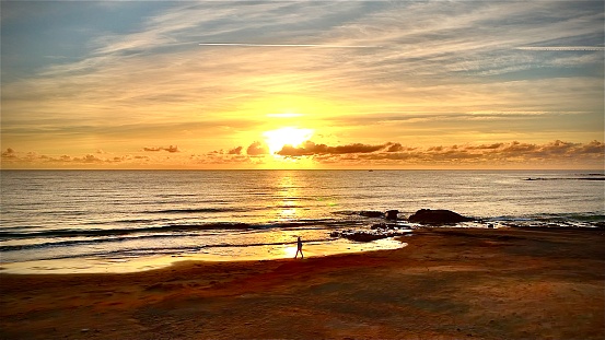 Aerial shot of an amazing sunrise at El Medano beach, Tenerife (Canary Islands) and the silhouette of a person walking on the beach