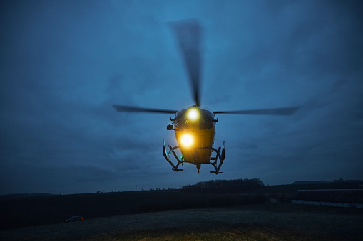 Flying helicopter of emergency medical service during take off from meadow at dusk. Themes rescue, help and hope.