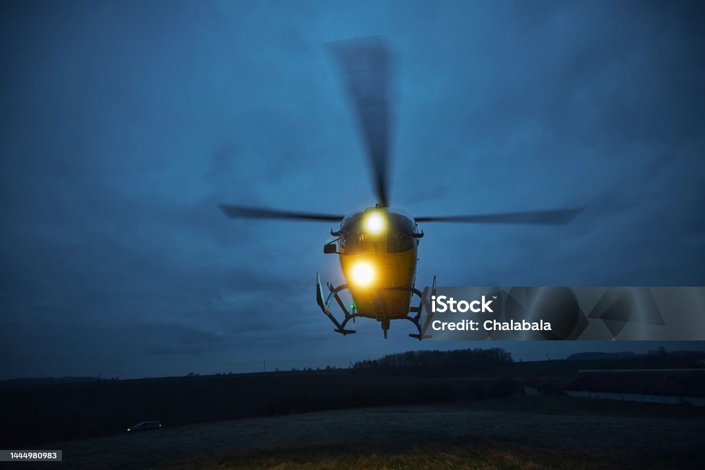 Flying helicopter of emergency medical service at dusk Flying helicopter of emergency medical service during take off from meadow at dusk. Themes rescue, help and hope. Helicopter Stock Photo