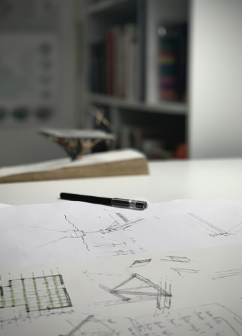 Architectural sketches with a pen on desk. Close-up of architect's working desk with building drawings.