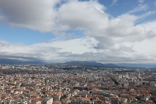 View from the top of a hill in Marseille France. Buildings and rolling hills in the distance.