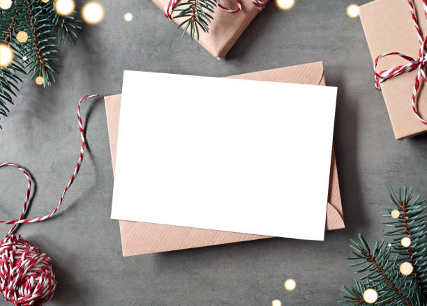 istock Blank white paper card with brown envelop, Christmas pine and handmade gift box on grey background. 1444985779