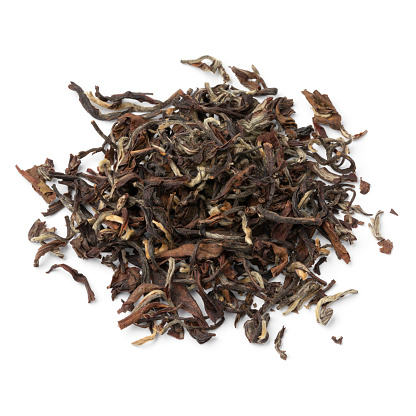 Heap of Phuguri Darjeeling Tea dried tea leaves close up isolated on white background