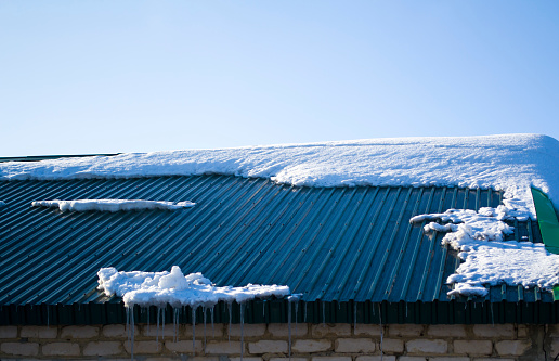 Icicles hang from the iron green roof, spring melting snow. High quality photo