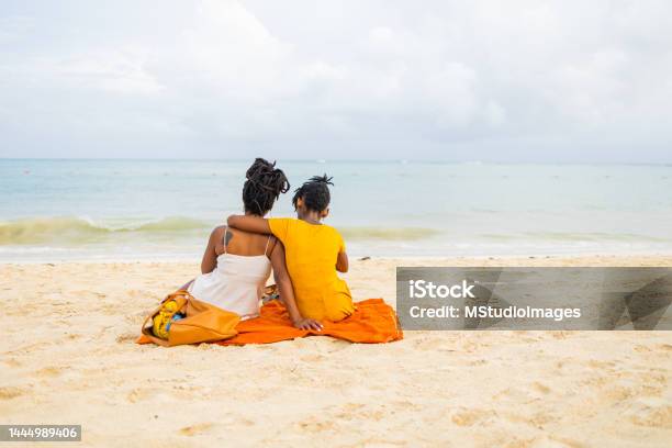 Mother and daughter sit on the beach and watch the waves