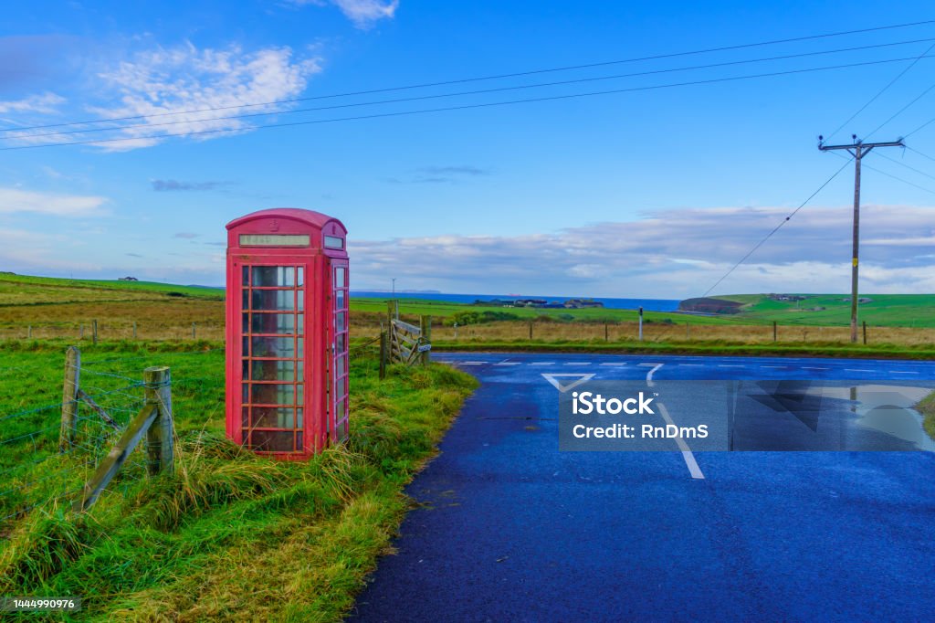 Red phone box, in landscape of fields, Orkney Islands View of a red phone box, in a landscape of fields with road, in the Orkney Islands, Scotland, UK Agricultural Field Stock Photo