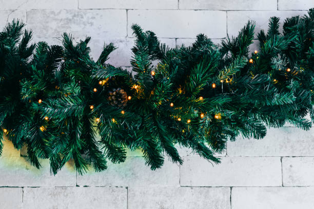 istock Christmas fir tree with lights on white brick background with copy space 1444996902