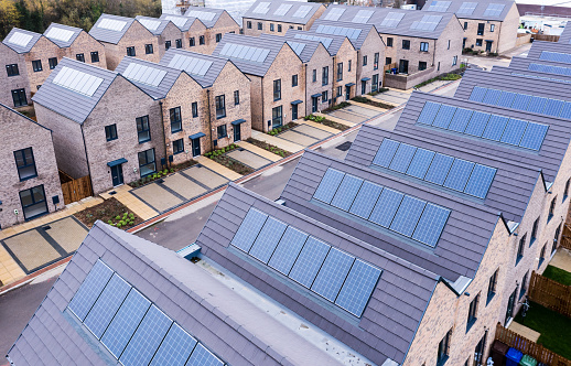 Aerial view of rows of energy efficient new build modular terraced houses in the UK with characterless design and in built rooftop solar panels for first time buyers