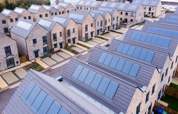 Characterless and energy efficient new build modular homes with rooftop solar panels Aerial view of rows of energy efficient new build modular terraced houses in the UK with characterless design and in built rooftop solar panels for first time buyers housing development stock pictures, royalty-free photos & images