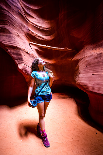 Young woman standing in desert landscape in Upper Antelope Canyon with sandstone rock curve formations wall in summer