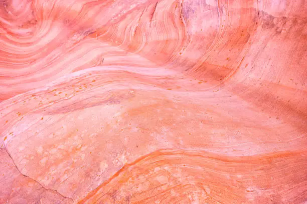 Photo of Macro closeup abstract red pink colorful sandstone rock formation layers of wave pattern on rock cliff in Gifford Canyon trail Utah Zion National Park