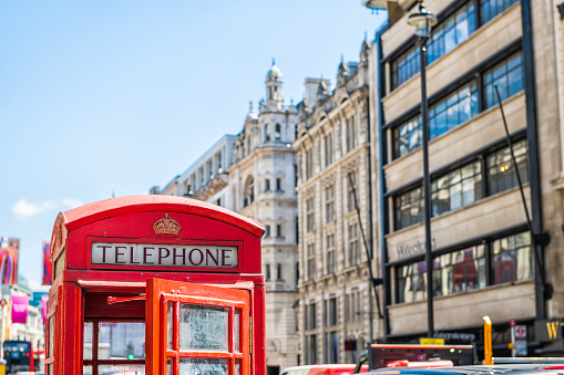 European red telephone phone box booth closeup with opened door in London, United Kingdom at Piccadilly circus street in summer