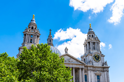 City of London, UK with St Paul's Cathedral of cupola dome exterior architecture, blue sky in downtown in summer with green trees foliage