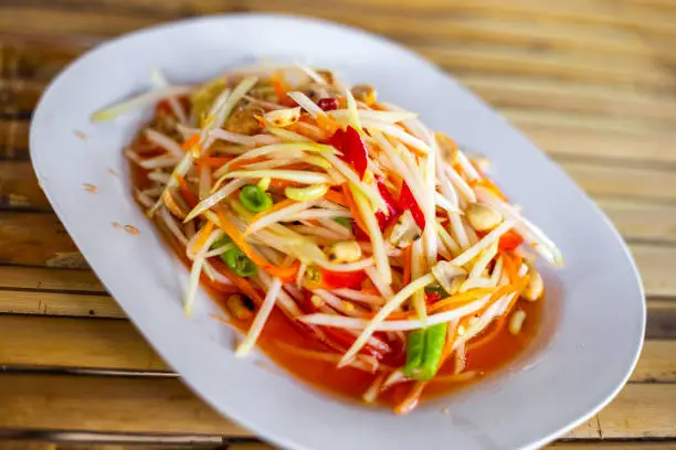 Som Tam salad dish with green papaya and hot chili peppers, selective focus. Thai food.