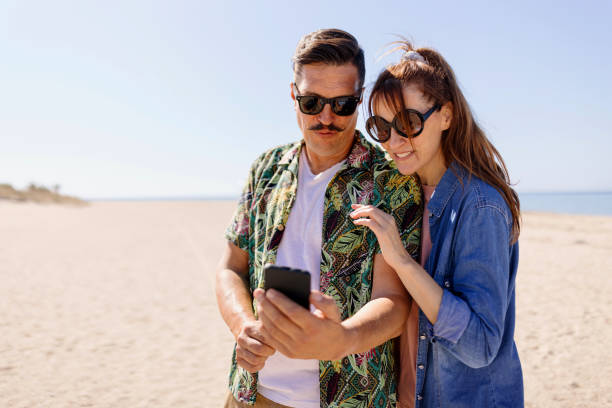 istock Mature couple looking at phone on the beach 1444999979