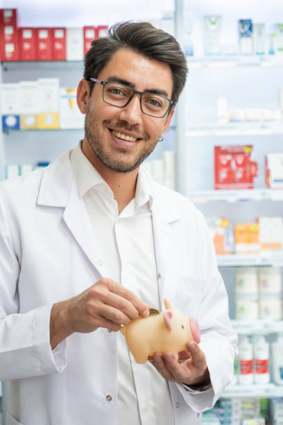 young pharmacist throws money into piggy bank stock photo