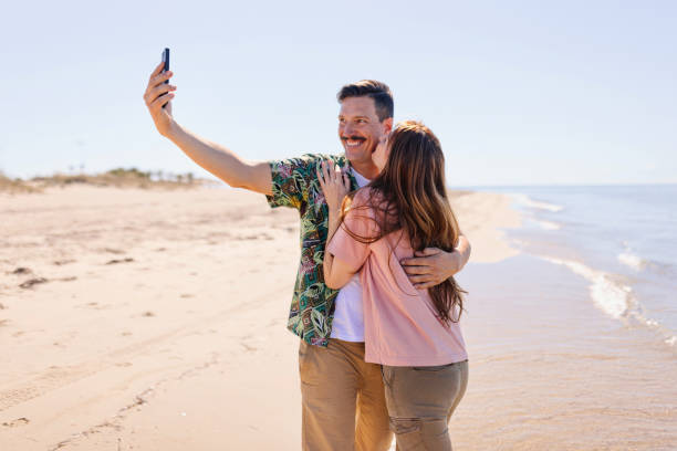 istock Middle aged couple in love taking selfie on the beach 1445002312