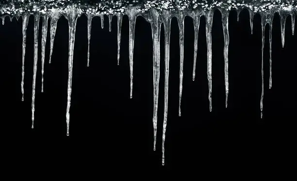 Photo of Icicles hanging isolated on black background. Winter background. Weather. Climate. Ice. Cut out