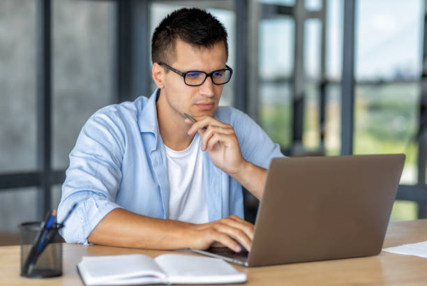 istock Focused man entrepreneur with glasses working looking at laptop screen thinking about something intently while sitting in the office 1445006678