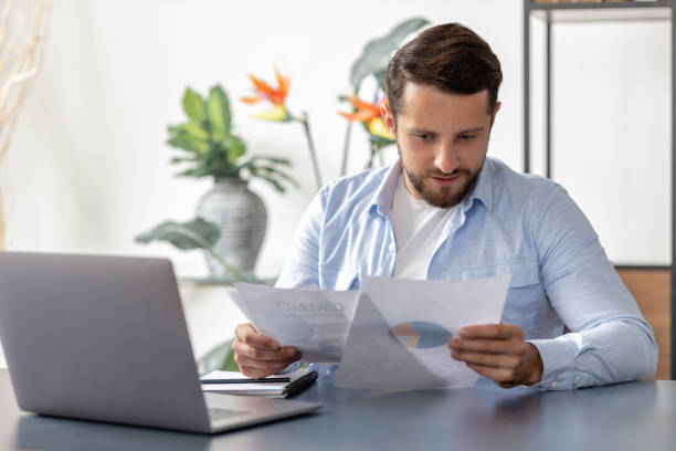 istock Busy male entrepreneur working with papers, checking financial reports. Businessman analyzes the report sitting at the table in the office 1445006809